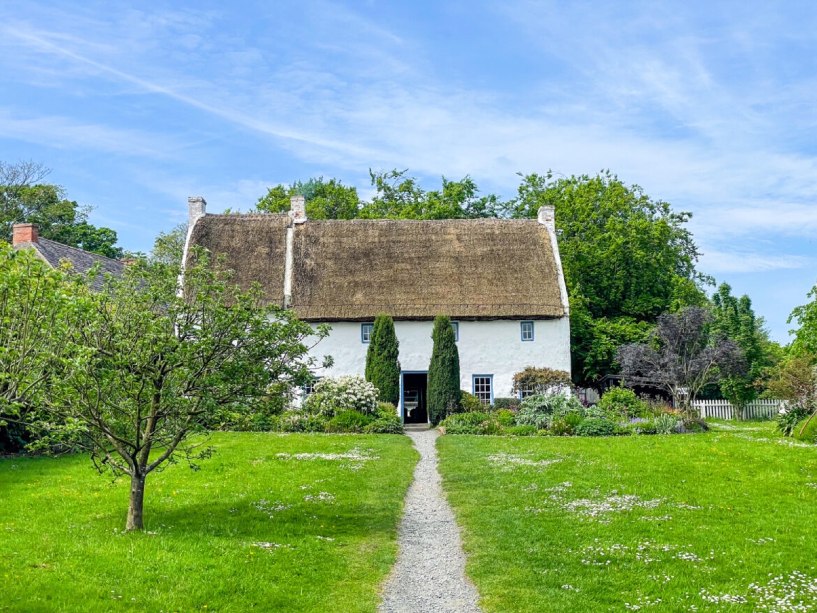 A whitewashed thatched cottage with a flowering cottage garden and path at the Ulster Folk Museum