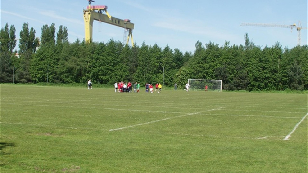 Football pitches at Victoria Park with the Harland and Wolff crane rising behind the trees
