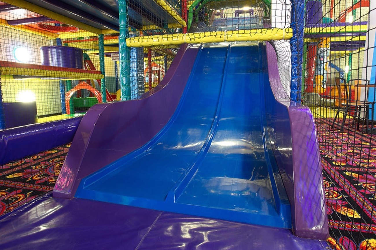 The big blue slide inside Wacky Workshop's three-level soft play frame, with climbing nets and colourful play features around it
