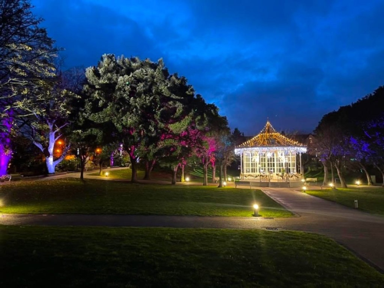The bandstand and trees lit in colour at night in Warrenpoint Municipal Park