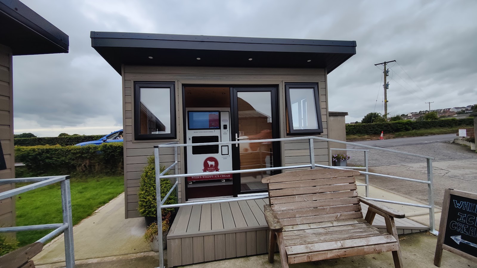 The Weir Farms self-serve cabin, a timber building with a bench outside and the County Down fields behind