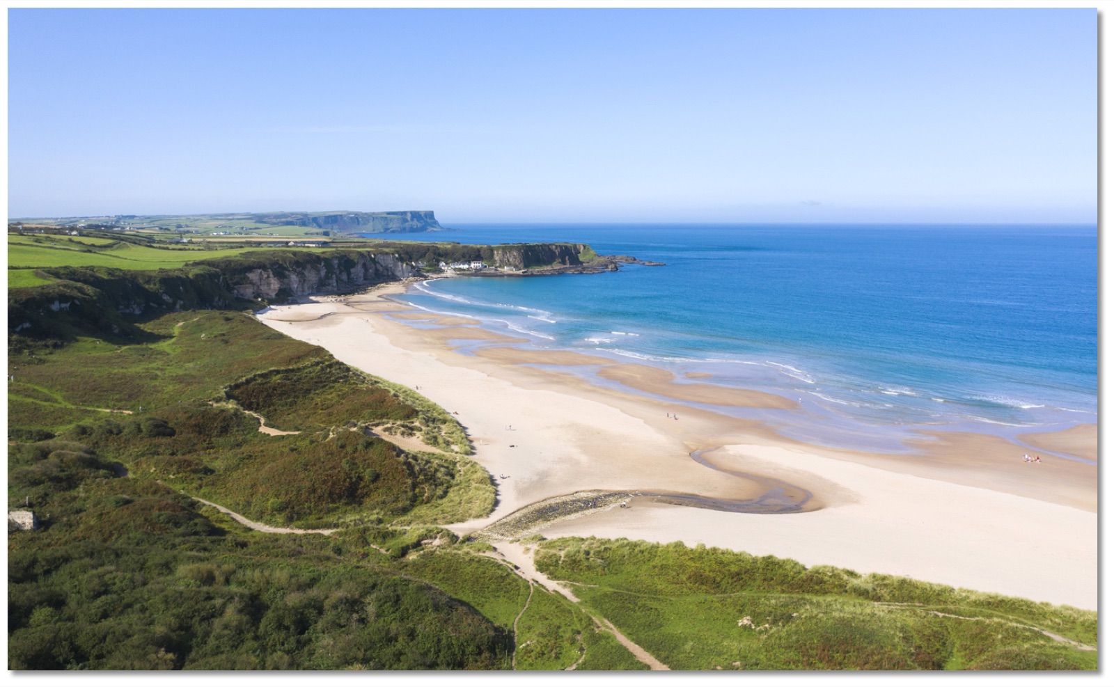 The wide white-sand crescent of White Park Bay curving between green headlands on the Antrim coast, seen from the dune cliffs