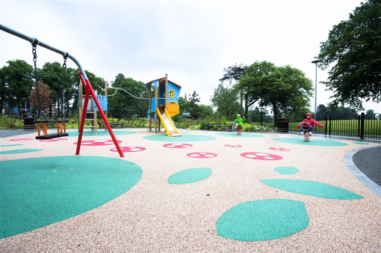 The children's play area at Woodvale Park with bright surfacing, swings and climbing frames