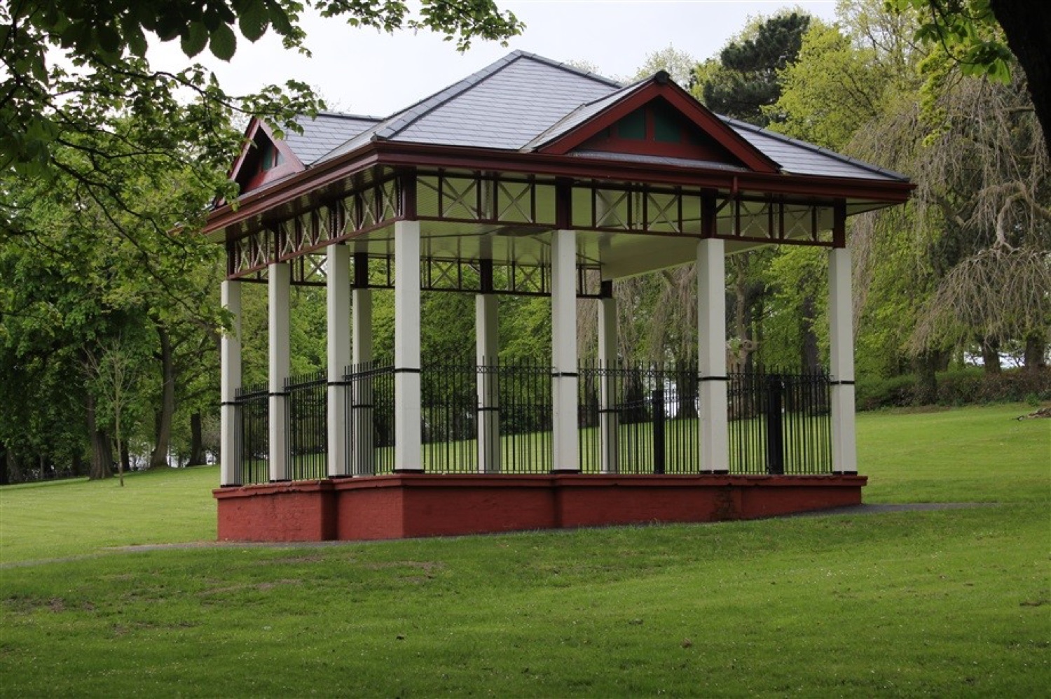 The restored bandstand at Woodvale Park with its red and cream ironwork standing on the green